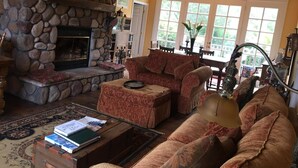 A cozy living room with a stone fireplace, a comfortable sofa, and a coffee table with books. - Pescadero Creek Inn (Pescadero)