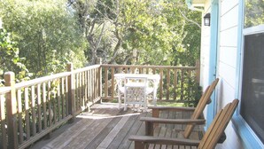 A wooden deck with a table and chairs, surrounded by trees. - Pescadero Creek Inn (Pescadero)