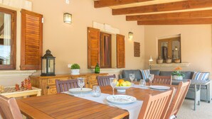A dining area with wooden tables and chairs, a chessboard, and a fruit bowl. - FINCA MIRALLES - Villa with private pool in Búger. Free WiFi (Búger)