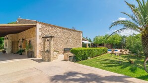 A stone building with a covered entrance, a paved driveway, and a well-maintained lawn with a palm tree. - FINCA MIRALLES - Villa with private pool in Búger. Free WiFi (Búger)