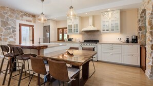 A modern kitchen with a central island, bar stools, and a stone accent wall. - FINCA MIRALLES - Villa with private pool in Búger. Free WiFi (Búger)