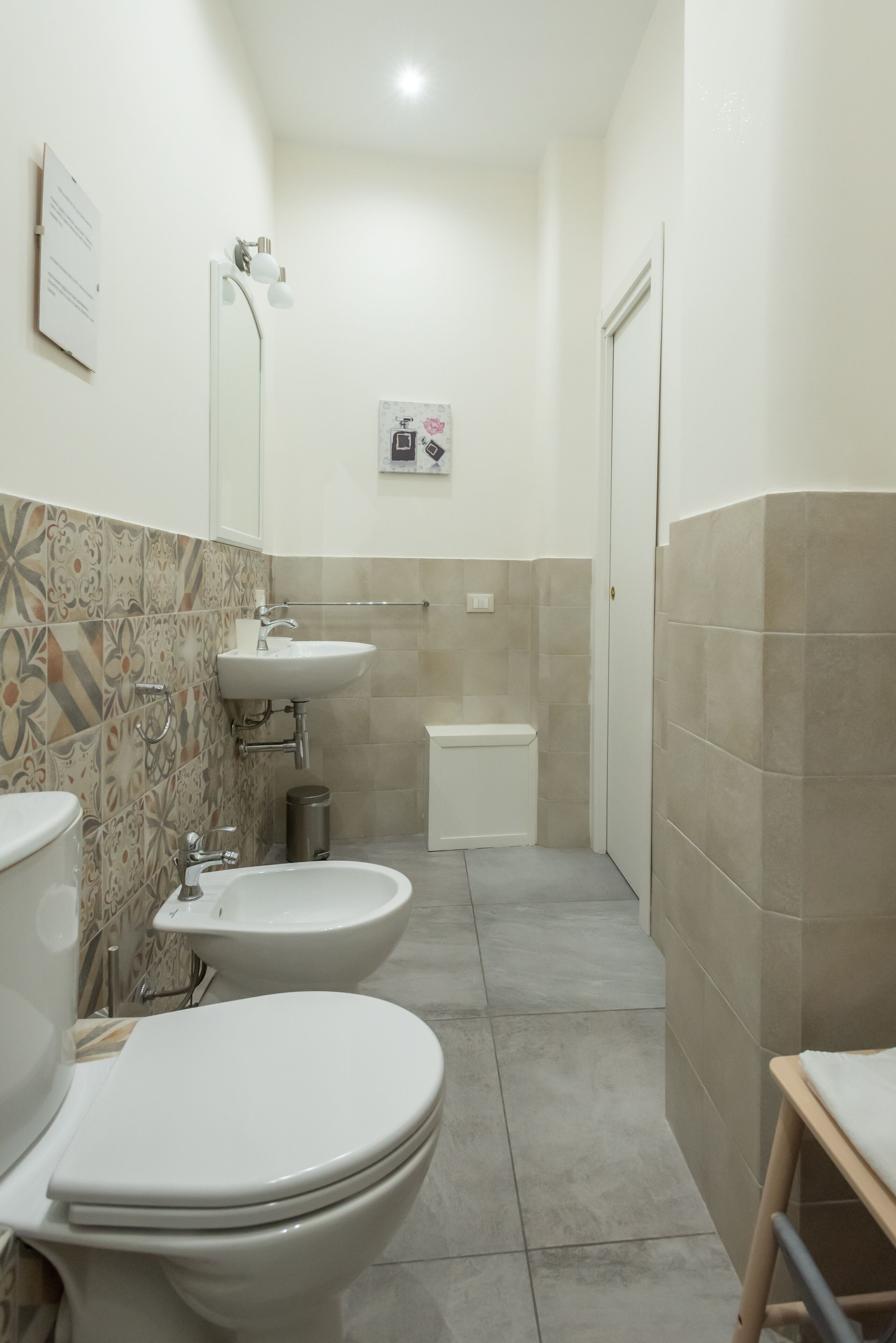 A bathroom with two toilets, a sink, a bidet, and a shower.