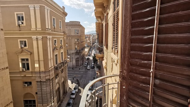 Una calle estrecha flanqueada por edificios, con balcones y unidades de aire acondicionado.