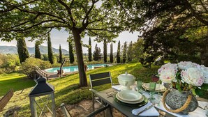 An outdoor dining setup with a table, chairs, and a view of a swimming pool and trees. - VILLA D'AMICO, charming indulgence overlooking Lucca Town Centre (Lucca)