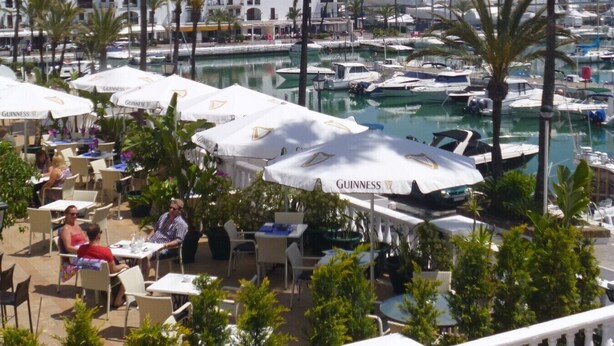 A marina with boats, outdoor seating with umbrellas, and palm trees. - Residencial Duquesa 2049  Manilva Beach (Manilva)