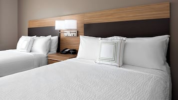Habitación de hotel con dos camas, una mesita de noche con lámpara y teléfono.