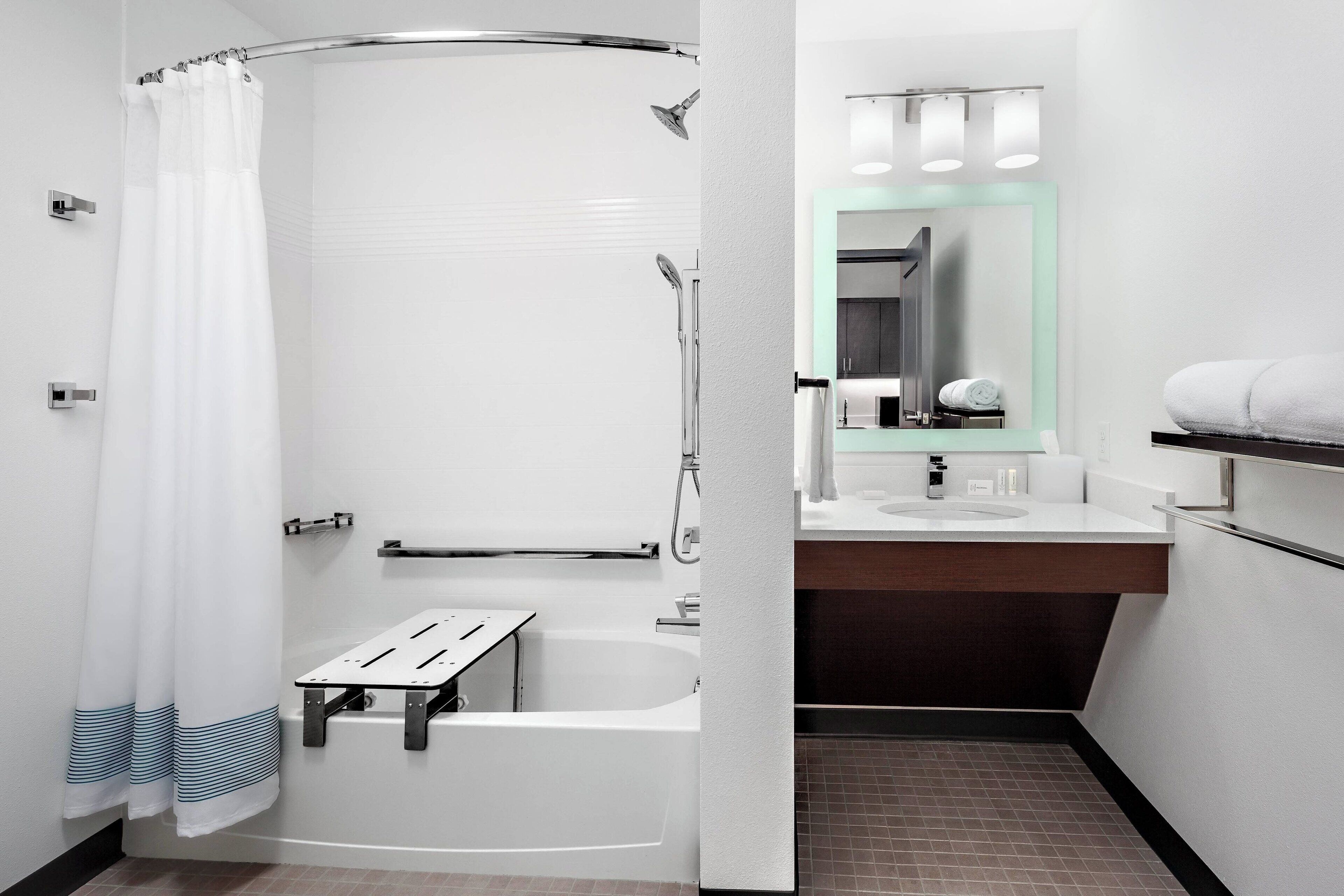 A modern bathroom with a shower, a bathtub, a vanity with a mirror, and a towel rack.