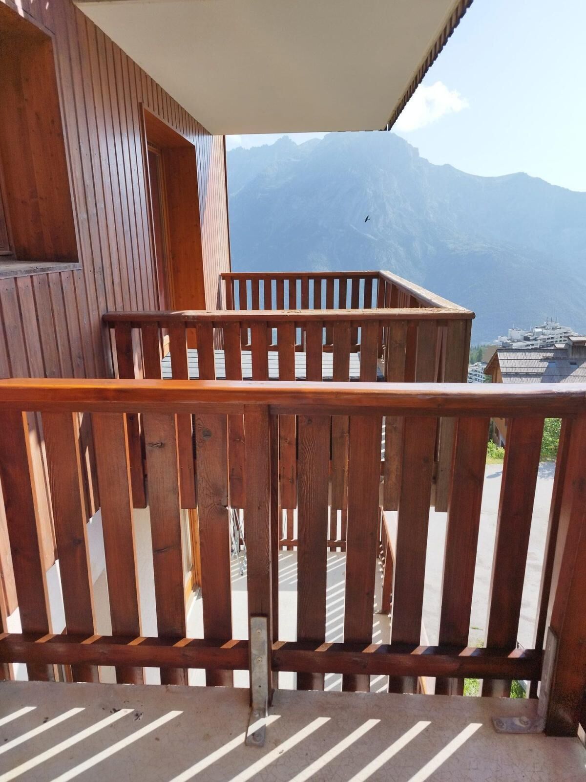 A wooden balcony with a view of mountains.
