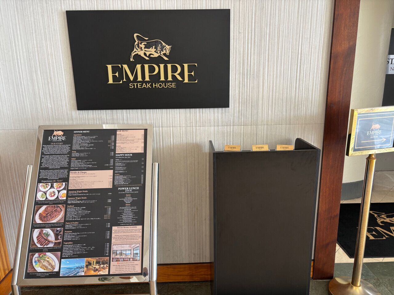 Un panneau affichant le menu du restaurant et une enseigne pour l’Empire Steak House.