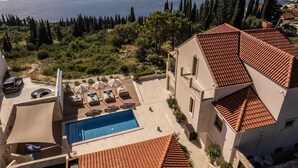 A villa with a swimming pool, outdoor seating, and a view of the sea.