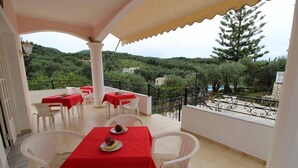 Una terraza con mesas y sillas, vistas al campo y una barandilla de balcón.