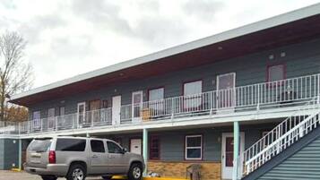 Un motel con una struttura a due piani, un'area di parcheggio coperta e una scala che conduce al livello superiore.