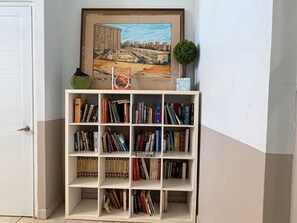 Una estantería con varios libros y un cuadro enmarcado de un paisaje urbano.