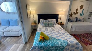 Un dormitorio con una cama, una mesita de noche, una lámpara, un sofá y decoración en la pared.