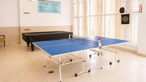 Une pièce équipée d’une table de ping-pong, d’une table de billard et d’un jeu de fléchettes.