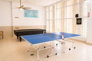 Una sala con mesa de ping pong, mesa de billar y dardos.