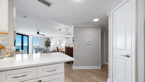 Una cocina moderna con armarios blancos, una encimera y un comedor con mesa y sillas.