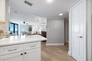 A modern kitchen with white cabinetry, a countertop, and a dining area with a table and chairs.