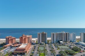 A coastal hotel complex with multiple high-rise buildings, a parking area, and a beach in the background. - ORANGE BEACH RETREAT, GREAT VIEW OF THE PASS, GREAT AMENITIES, GREAT FOR FAMILY (Orange Beach)