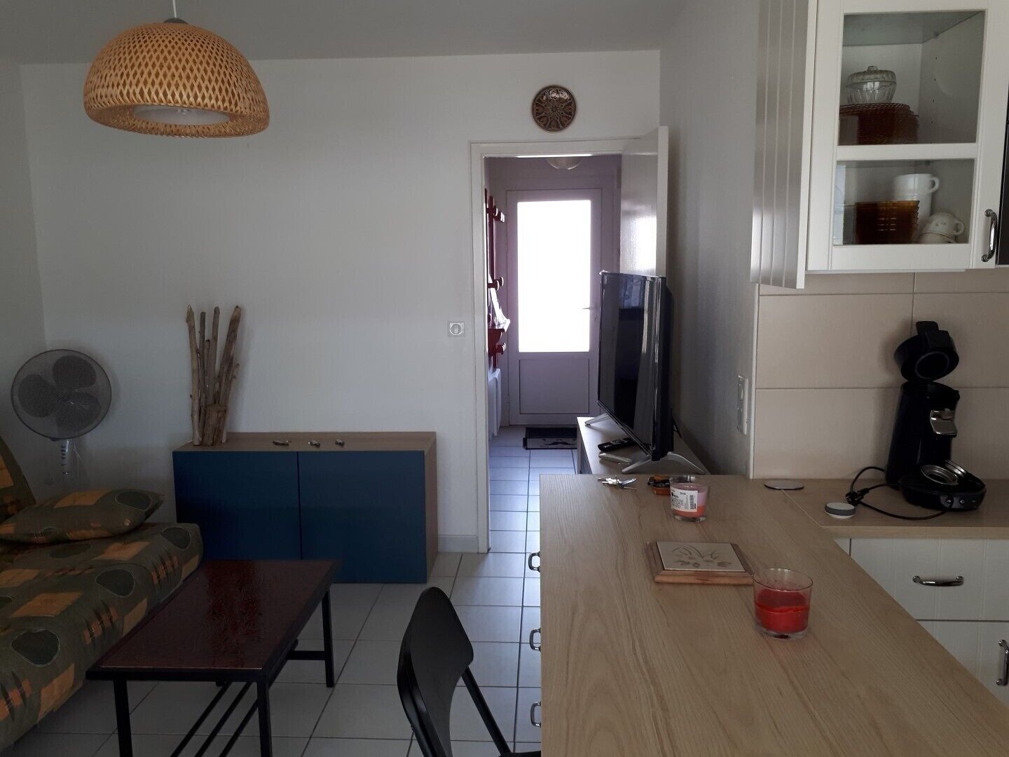 A compact living space with a dining area, kitchenette, and a television.