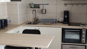 Une cuisine moderne dotée d’un plan de travail en bois, d’un four encastré, d’un évier et d’un luminaire suspendu.