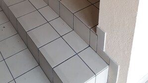 Un escalier recouvert de carreaux beiges et doté d’une main courante en bois.
