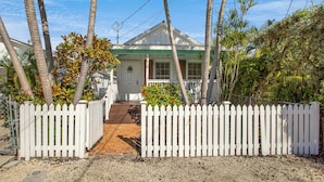 A white house with a green roof, a white picket fence, and a gravel driveway. - HEMINGWAY'S HIDEOUT ~ Historic Old Town Cottage with Pool! (Key West)
