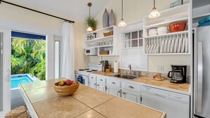 A modern kitchen with a large island, white cabinetry, and a view of a pool. - HEMINGWAY'S HIDEOUT ~ Historic Old Town Cottage with Pool! (Key West)