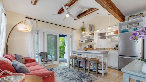A modern kitchen with white cabinetry, a central island, and a built-in refrigerator. - HEMINGWAY'S HIDEOUT ~ Historic Old Town Cottage with Pool! (Key West)