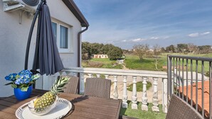 Un balcon avec une table, un ventilateur et une plante en pot.