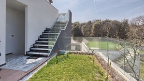 Une maison moderne avec un escalier en verre menant à une terrasse.