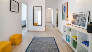 A hallway with a mirror, framed pictures, a yellow ottoman, and a bookshelf. - Beautiful apartment for 6 people with A/C, WIFI, TV and patio (Binissalem)