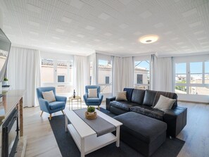 Ein großzügiges Wohnzimmer im modernen Stil, mit einem schwarzen Ledersofa, zwei blauen Sesseln, einem weißen Couchtisch und einem großen Fenster mit Blick auf die Stadt.