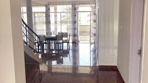 Un vaste hall d’entrée doté d’un sol en marbre qui mène à une salle à manger avec une table et des chaises.