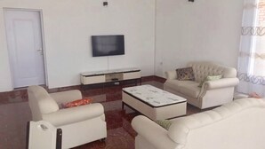 Un salon avec un téléviseur à écran plat fixé au mur, un canapé, une table basse et une porte.