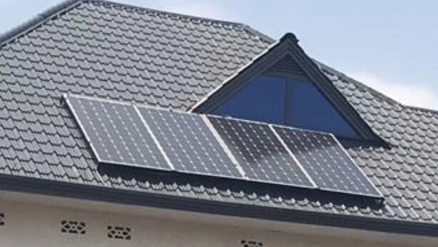 Un bâtiment doté d’un toit en pente, de panneaux solaires et de nombreuses fenêtres.