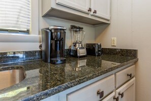 A kitchen with a granite countertop, a coffee maker, a blender, and a toaster.