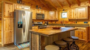 Une cuisine de style rustique, avec des éléments en bois, un îlot central, des appareils en acier inoxydable et des armoires en bois.