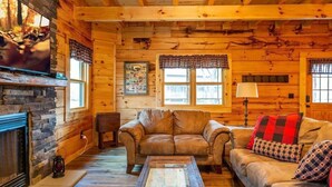 L’intérieur d’un chalet confortable, avec une cheminée en pierre, des canapés en cuir et un plancher en bois.