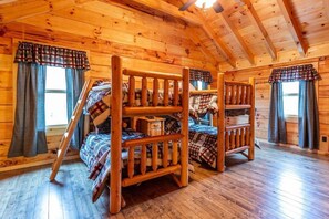 Une cabane dotée d’une chambre à l’étage, aménagée dans un style loft, avec des lits superposés et un plafond en bois.