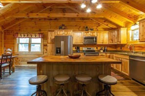 L'intérieur d'une cabane en bois comprend une cuisine, un coin repas et des tabourets de bar.