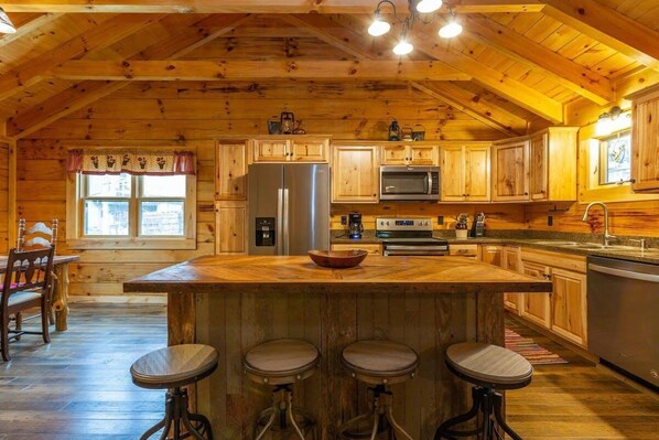 L'intérieur d'une cabane en bois comprend une cuisine, un coin repas et des tabourets de bar.
