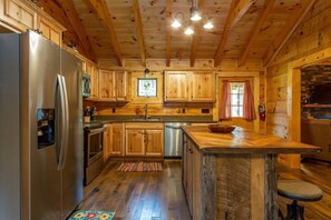 Eine Küchenzeile im Chalet-Stil mit Kühlschrank, Herd, Mikrowelle und Holzschränken.