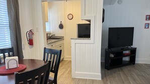 Un espace de vie compact comprenant un coin repas, une kitchenette et un meuble pour la télévision.