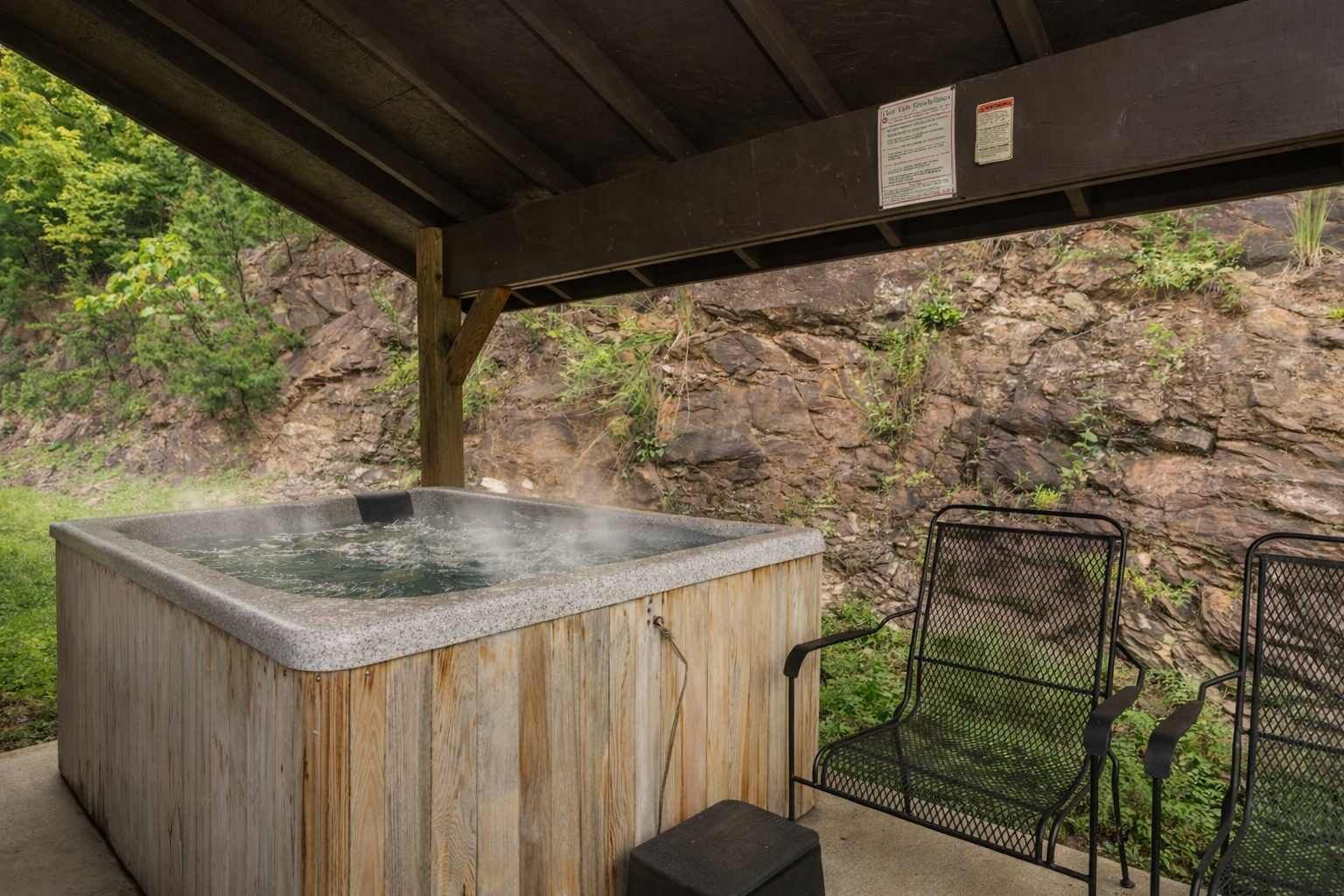 Un jacuzzi bajo una pérgola de madera con un fondo rocoso.