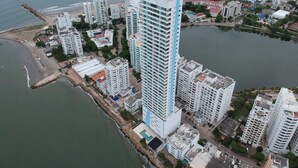 Ein hoch aufragendes Gebäude mit modernem Design, in der Nähe von Wasser gelegen und direkt an einem Strand.
