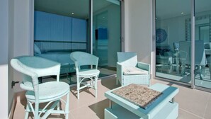 Ein Balkon mit Korbmöbeln, darunter zwei Stühle und ein kleiner Tisch.