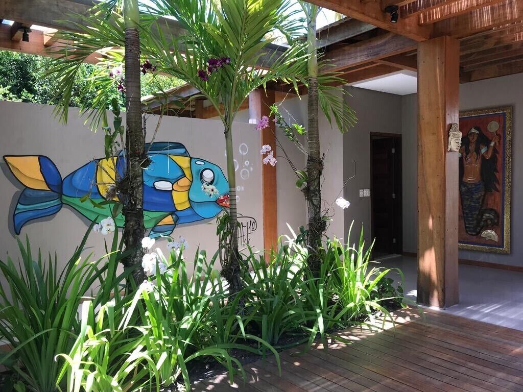 A modern interior with a wooden ceiling, a mural of a fish, and tropical plants. - Retreat with Full Club and Cook (Praia do Forte)