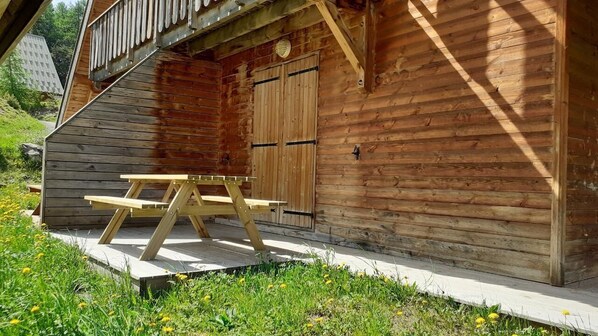 A wooden cabin with a picnic table and a door. - Chalet, 150m from resort center, swimming pool, sauna, terrace, parking, tv, ski locker, 43m² (Agnières-en-Dévoluy)