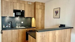 A kitchen with wooden cabinets, a black countertop, a microwave, and a sink.